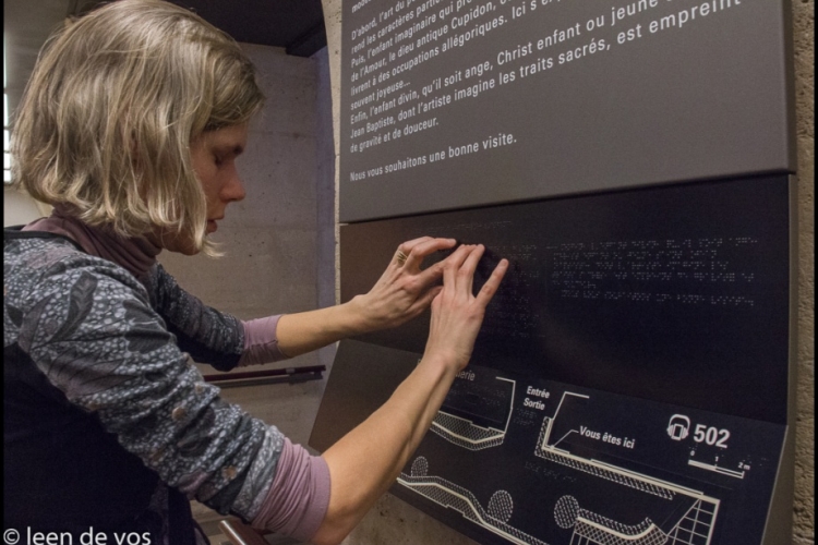 foto van Inge, een blinde bezoeker die een tactiel plan leest in het Louvre
